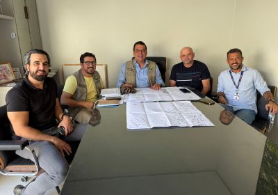 Prefeito Mariano Correntina reunido com equipe técnica e representantes da empresa contratada para a execução da Estação de Tratamento de Esgoto, analisando plantas e cronograma da obra no gabinete da Prefeitura de Correntina.